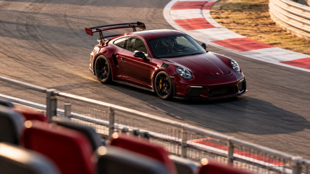 Grandstand perspective of a burgundy sports coupe on a circuit, illustrating Madring grandstand views coverage